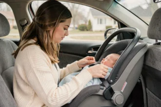 Mère installant son nouveau-né dans un siège auto infant homologué à bord d'une berline familiale