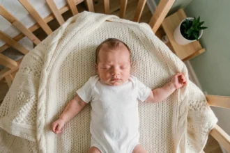Bébé de un mois photographié en vue du dessus allongé sur une couverture en tricot crème, première pose mensuelle pour suivre son évolution